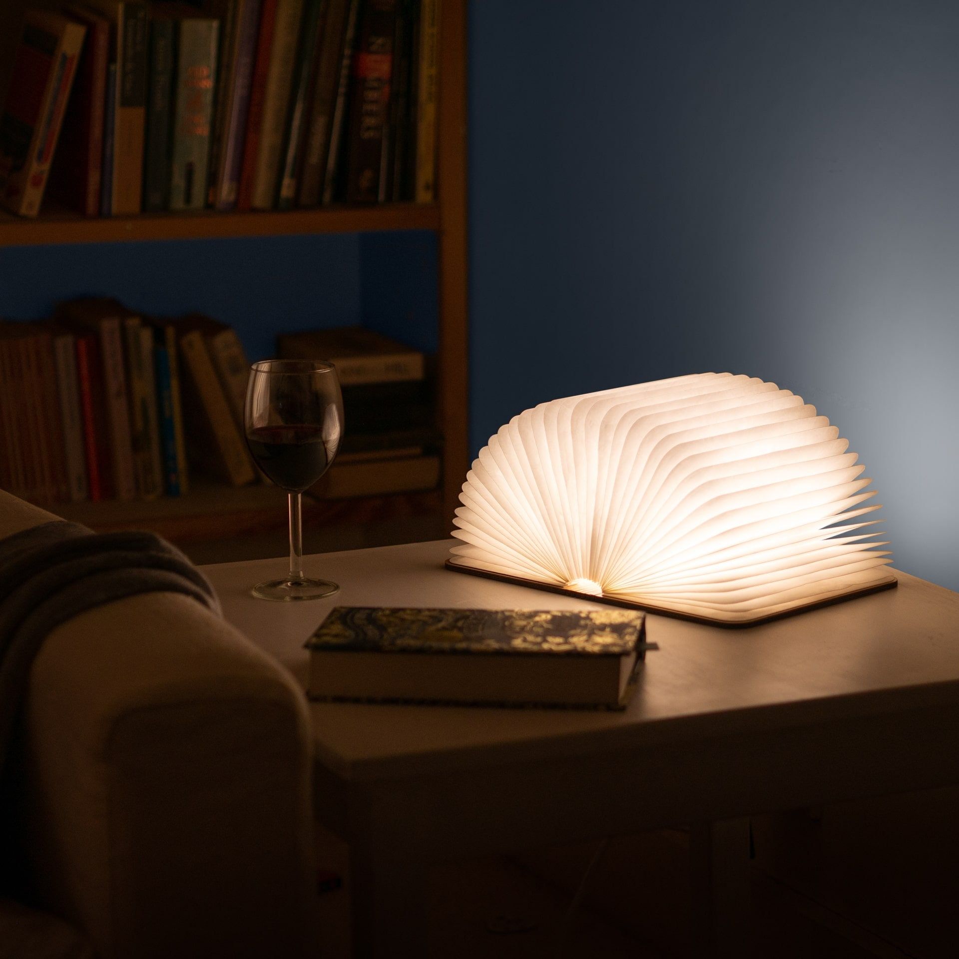 Open book resting on a folded blanket with gentle lamp glow